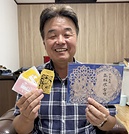 高松塚古墳の御朱印㊨と一願成就お守りを持つ浪江社長