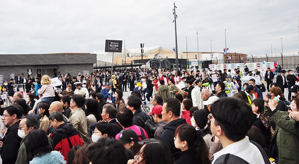 開幕後、夢洲駅から東ゲートに向かう参加者（13日）