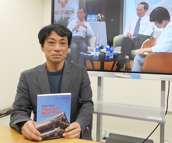 刊行の意義を語る箕浦暁雄教授。背後の写真は5月の出版記念イベントの様子