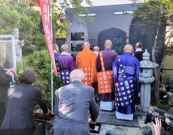 慰霊碑前で祈りを捧げる僧侶ら