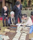 慰問資料に見入る湯次行隆住職（左から2人目）ら