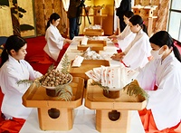 大福梅を奉書紙に包む巫女たち