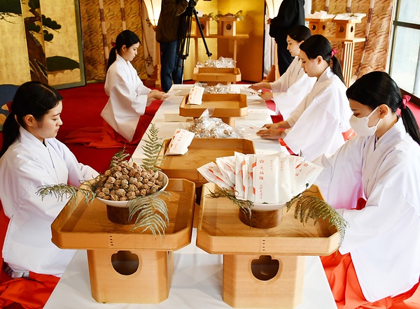 大福梅を奉書紙に包む巫女たち