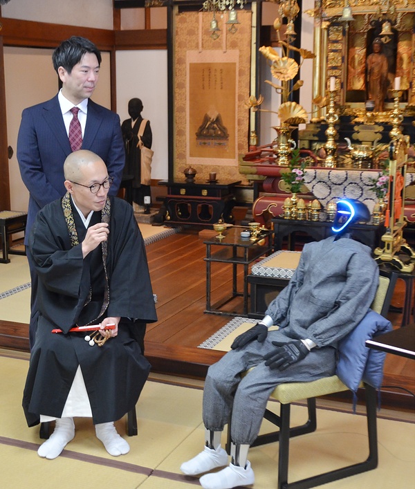 ブッダロイド㊨に質問する東伏見執事長。後方は熊谷教授