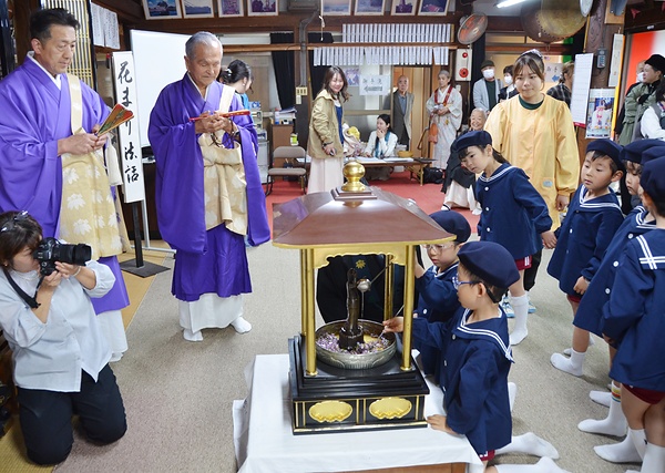 本堂で子どもたちの灌仏を見守る市橋玄義住職（左端）と愛爾前住職（その右隣）