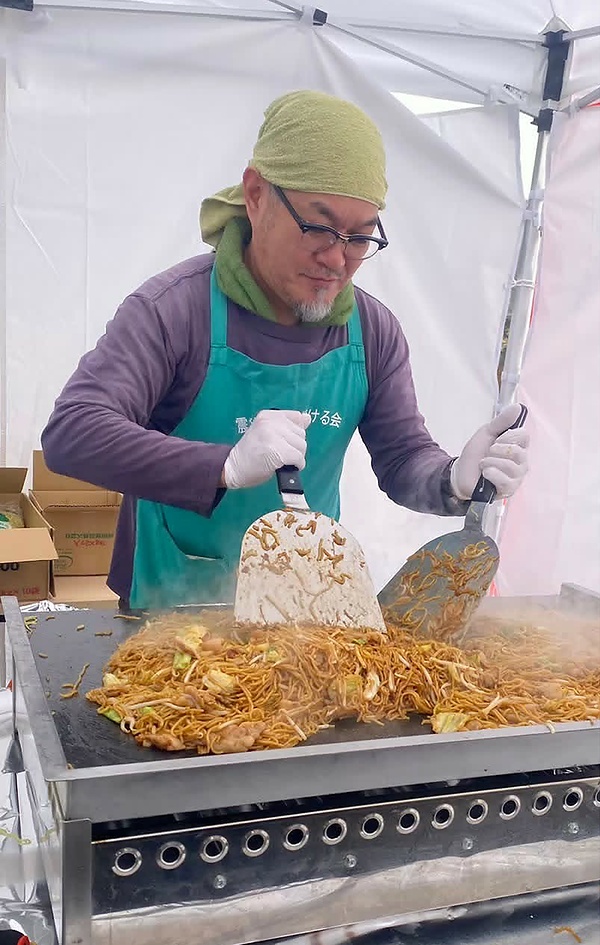 輪島市の温泉施設で開いた炊き出しで焼きそばを焼く石﨑住職（2025年11月）