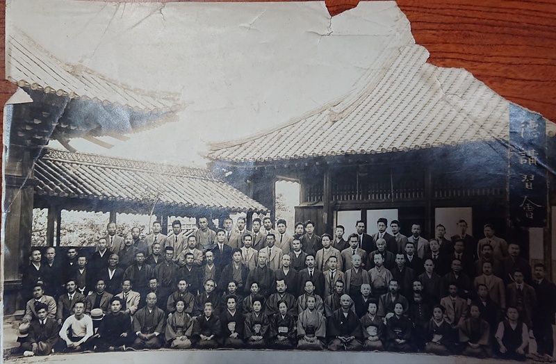 >図一　信徳講習会とみられる西光寺本堂を背景にした集合写真（西光寺蔵）：三列目中央には、照峰馨山と高橋正雄の姿がある。